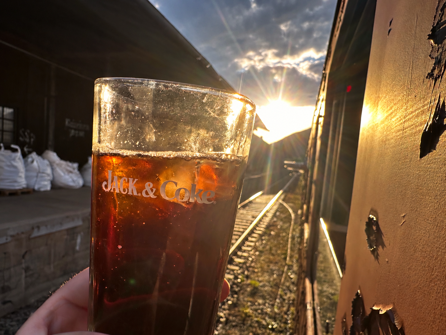 Getränkeglas im Sonnenlicht am Wagen entlang der Gleise