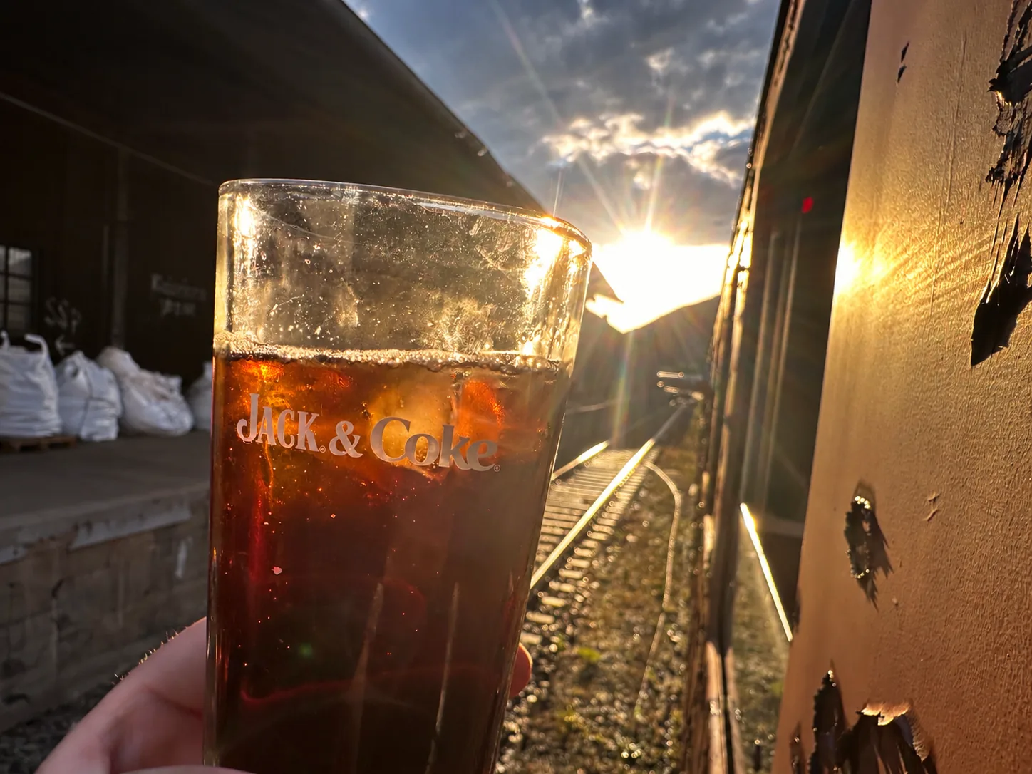 Getränkeglas im Sonnenlicht am Wagen entlang der Gleise
